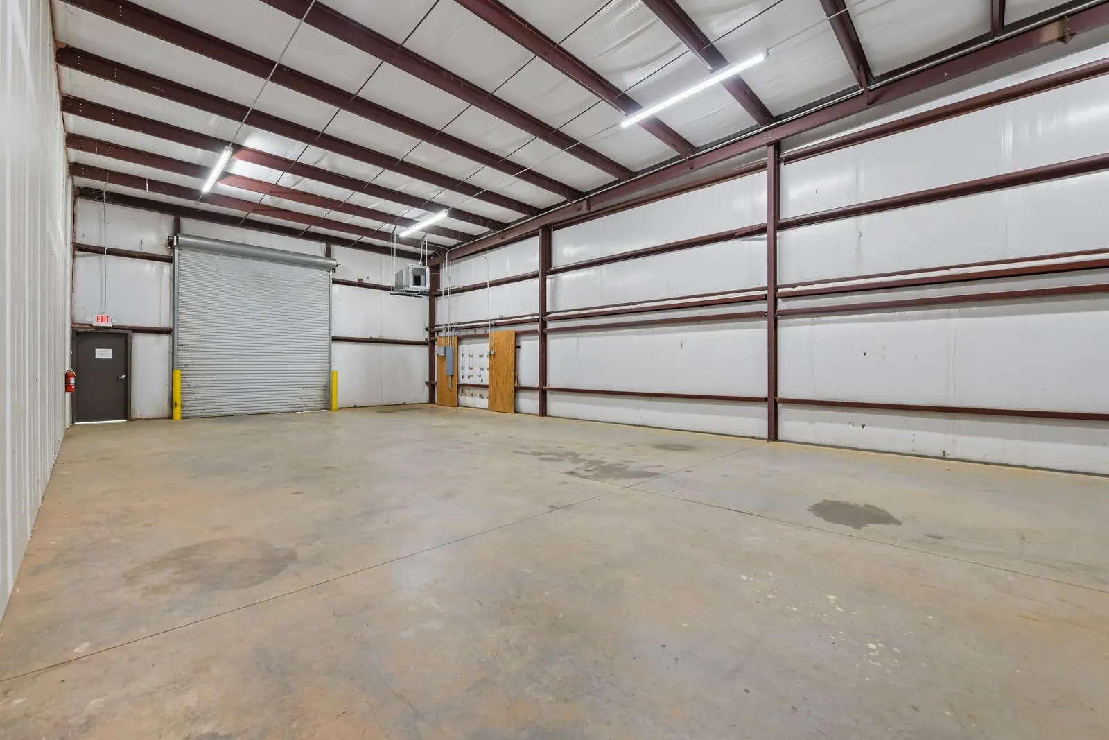 Before: a warehouse bay with white metal walls, a roll-up door and a stained concrete floor.