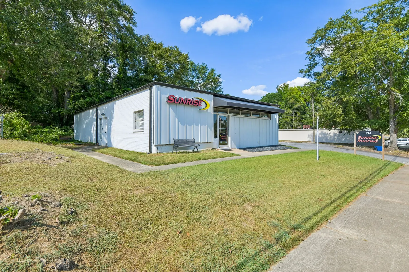 Before: a white commercial building with a red sign seen across a patchy, uneven front lawn.