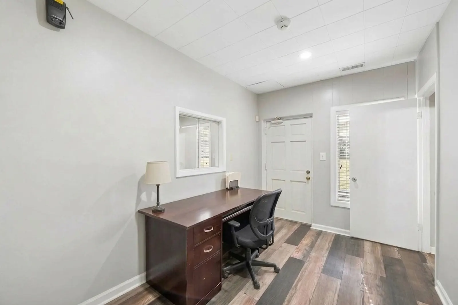 After: the same office with one desk, one chair and a lamp, the walls and floor clear.