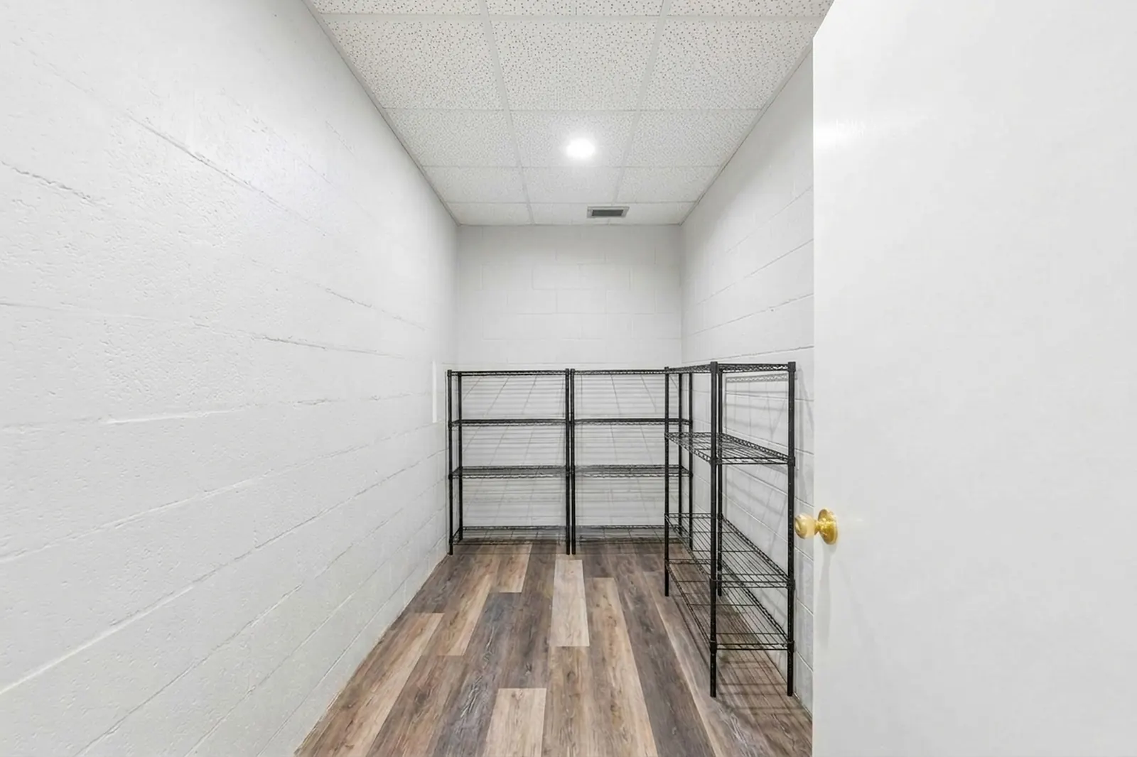 After: the same storage room emptied, showing clean wire shelving and plank flooring.